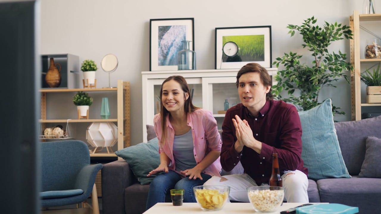 A man and woman sitting on a couch watching tv